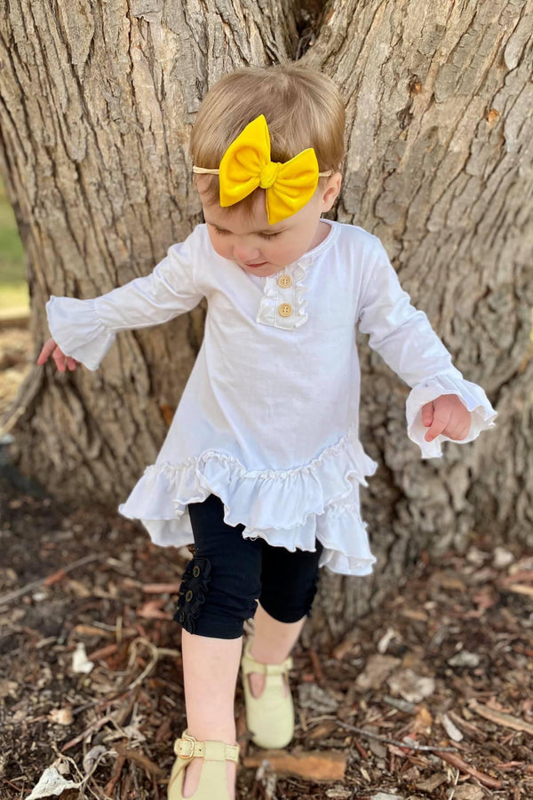 baby girl by a tree in black ruffle capri yellow velvet bow
