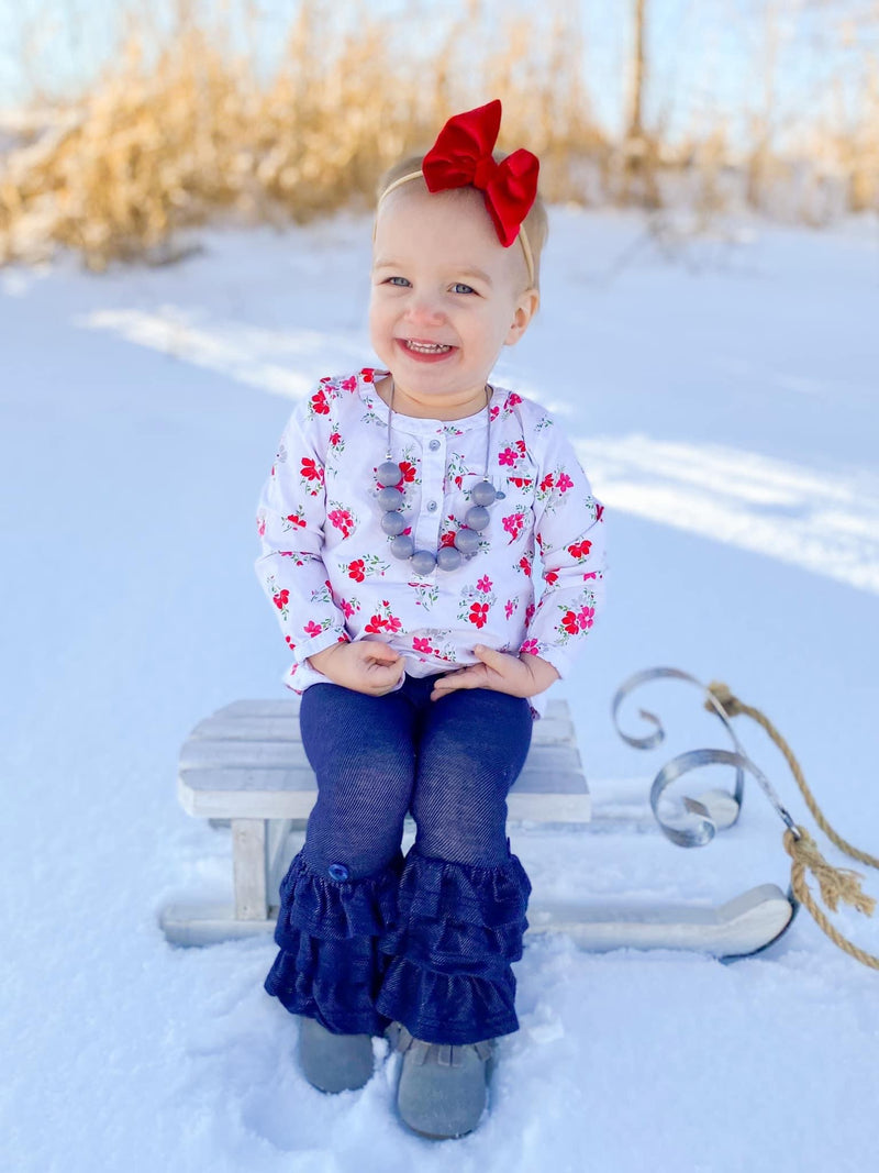 child on sleigh outdoor in blue bell jeans and red velvet mini bow